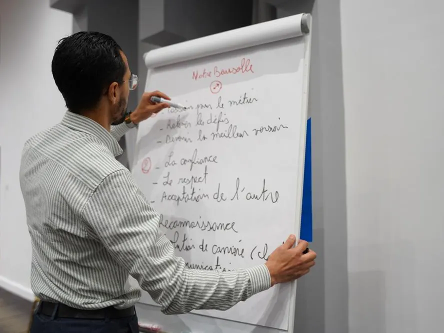 Un participant écrit au paperboard les engagements de son équipe.