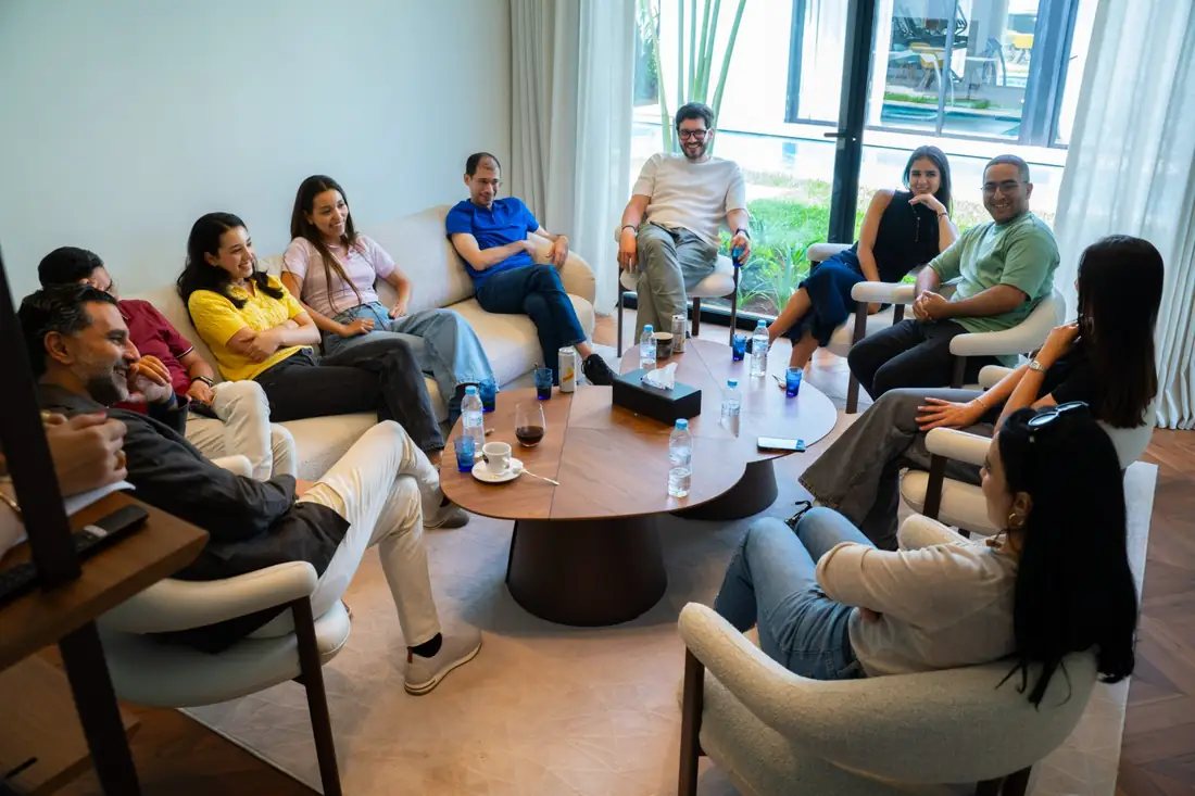 L'équipe au complet, assise en cercle dans un salon, en pleine discussion.