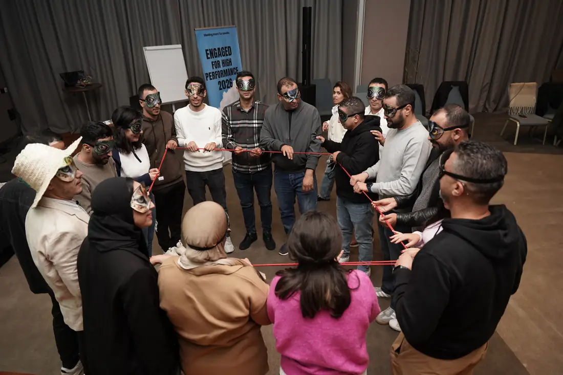 Les participants masqués forment un cercle et tendent une corde rouge.