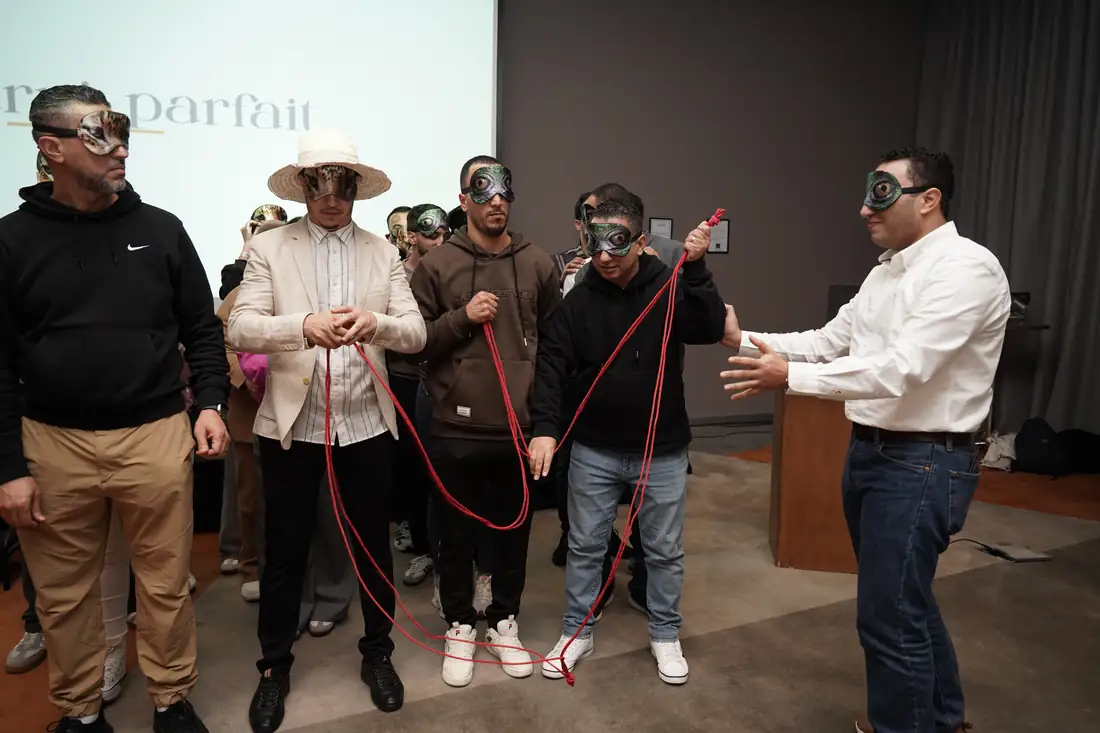 Un facilitateur guide quatre participants masqués qui tiennent la corde.